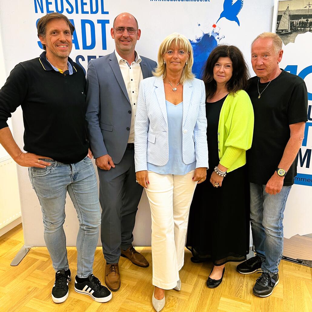 Neusiedl am See: Fünf Personen stehen vor einem Banner, ein Mann mit Brille und blauem Sakko im Zentrum.