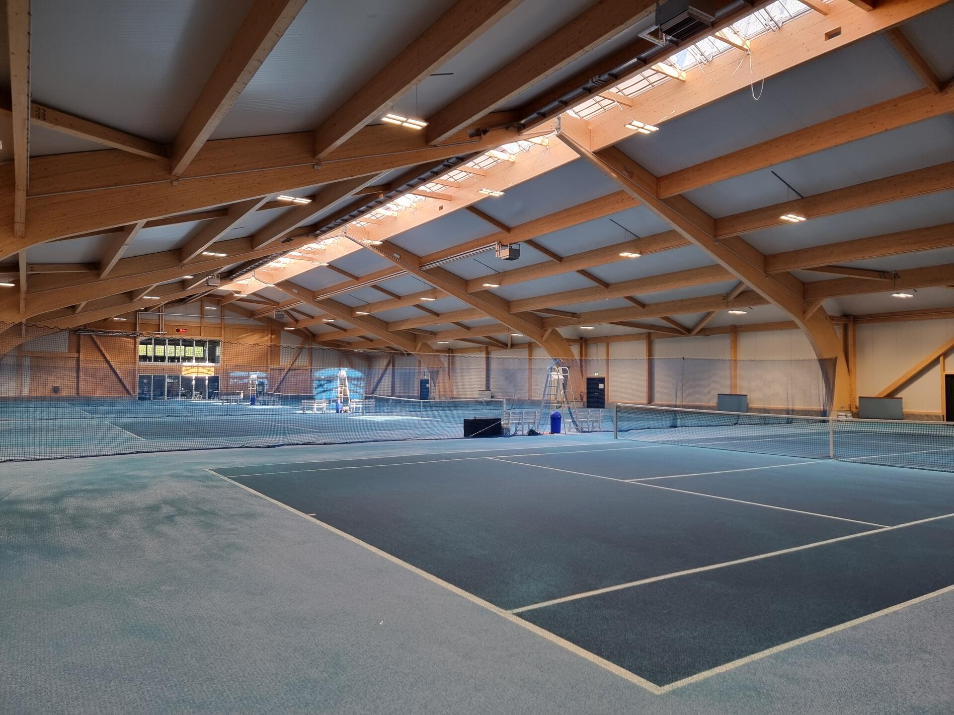 Blick in der Tennishalle von hinten nach vorne auf die vier Plätze.
