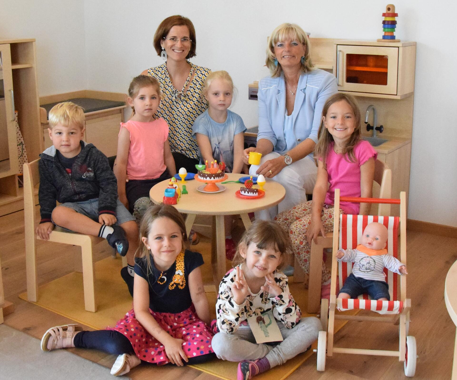 Bürgermeisterin LAbg. Elisabeth Böhm besucht den Kindergarten Storchennest. Sie sitzt mit Leiterin Evi Leopold und sechs Kindergartenkinder in der Spielecke.