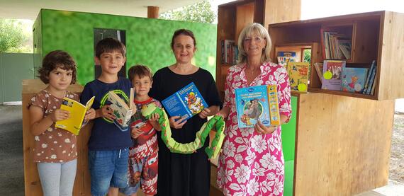 Die Bürgermeisterin besucht gemeinsam mit der Bereichsleiterin Elementarbildung Sabine Wegleitner und drei Kindergartenkindern den offenen Bücherschrank vor dem Montessori Kinderhaus.